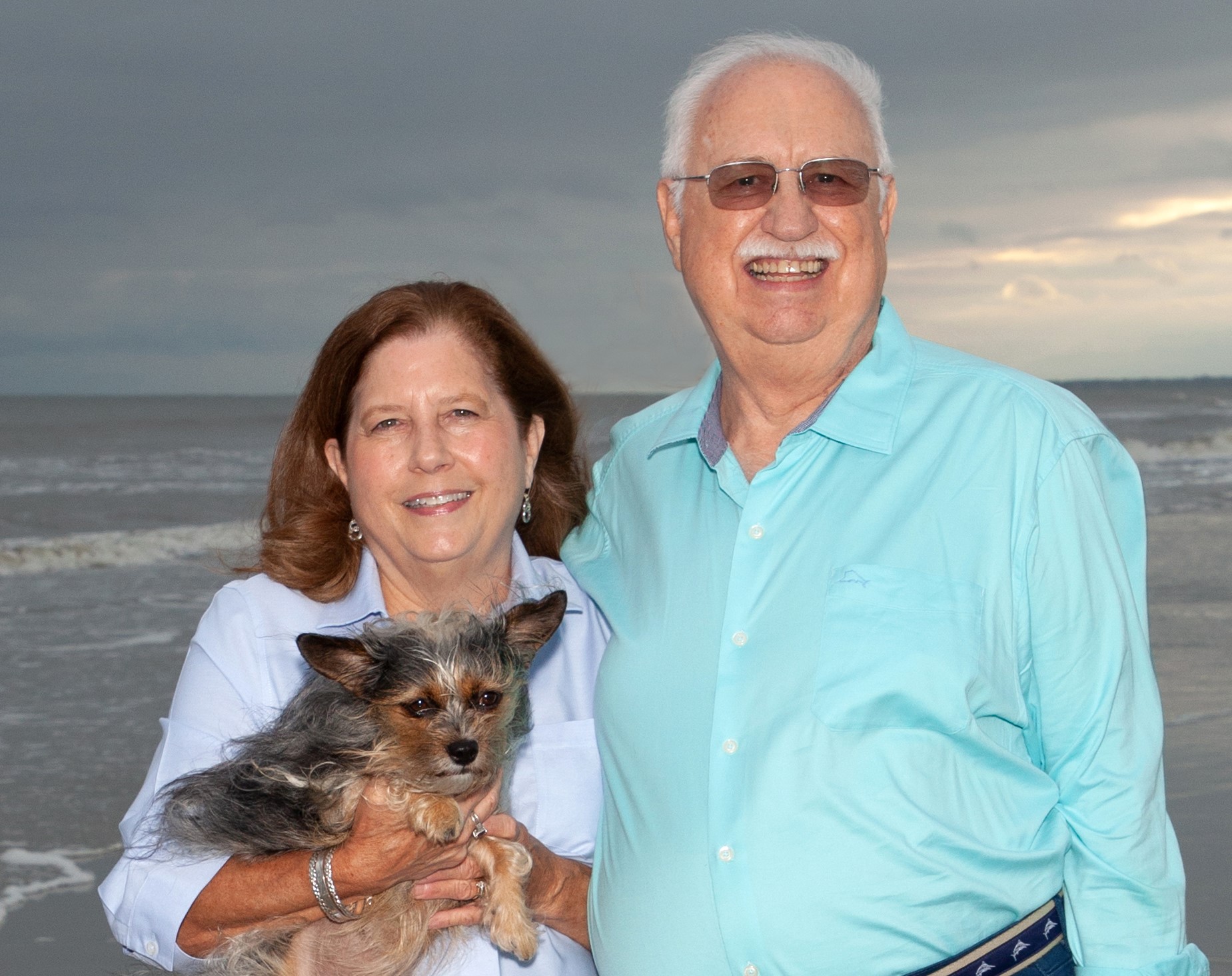 Smiling family posing with their dog in a beach